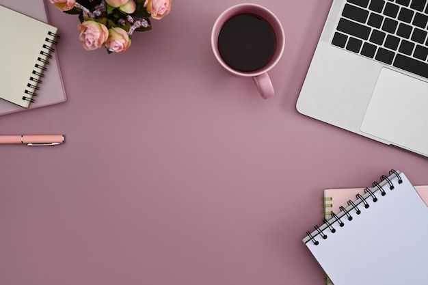 Local de trabalho feminino com xícara de café de computador portátil e notebook em fundo rosa Vista superior | Foto Premium